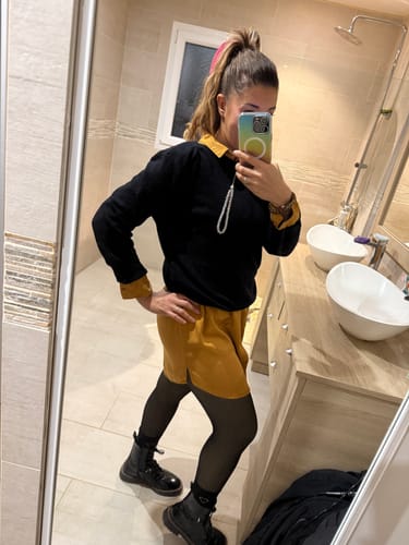 Une cliente porte le collant polaire noir effet transparent avec une robe et des bottes.