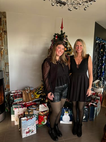 Deux clientes en tenue de fête portant le collant polaire noir devant un sapin
