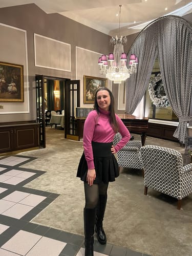 Cliente en col roulé rose et collant polaire noir, dans un hôtel décoré pour Noël